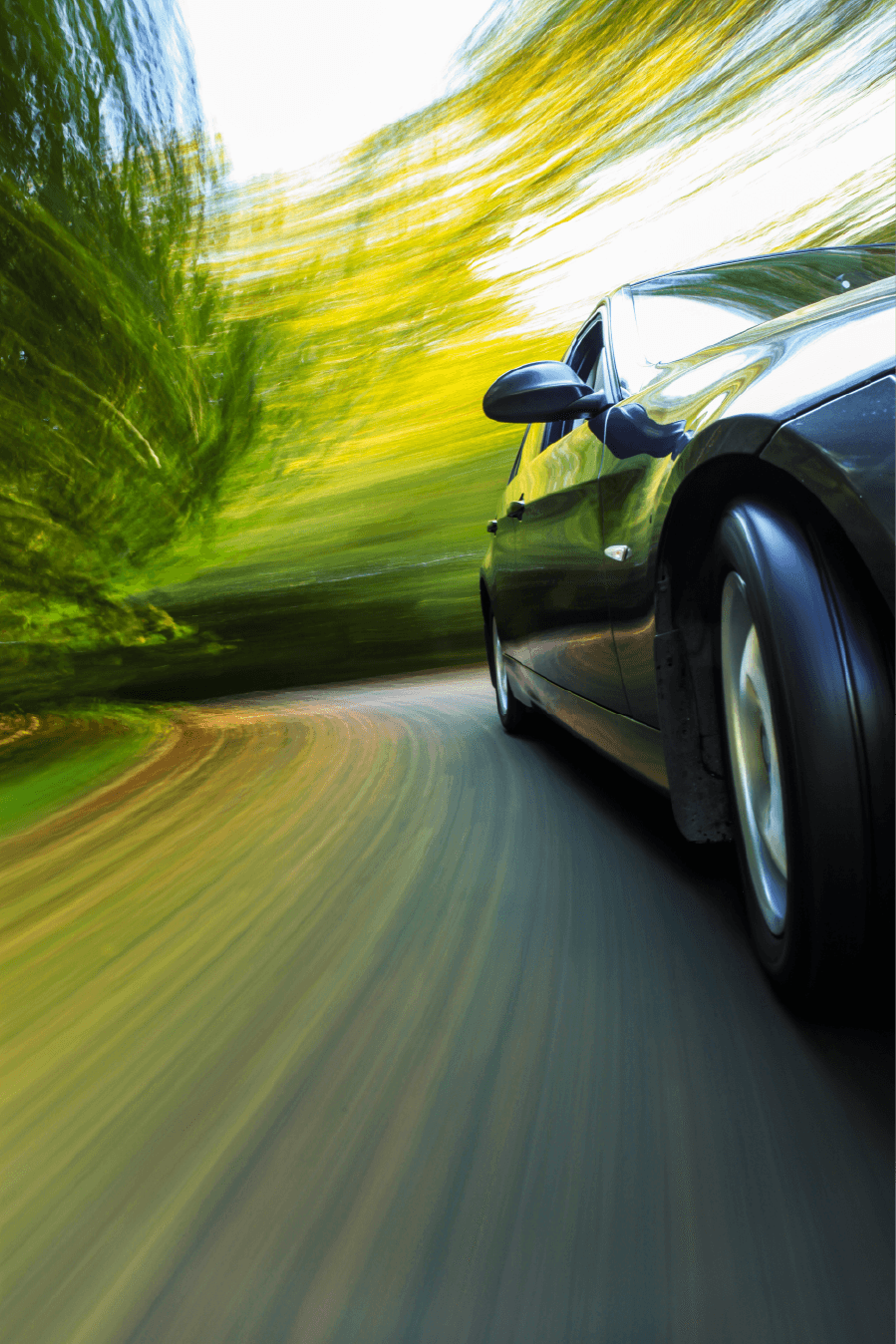Close-up image of a sports car speeding along country road